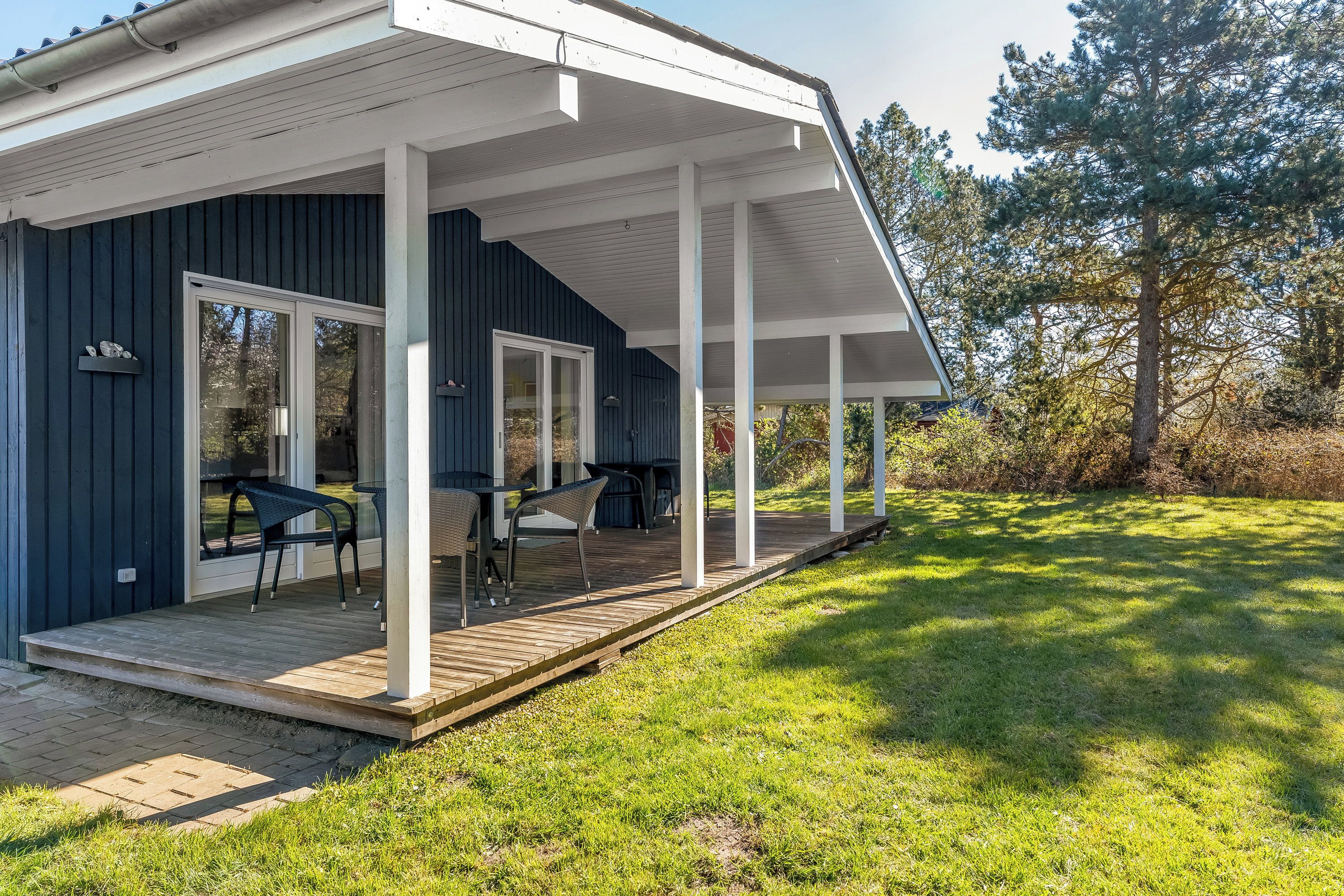 A covered outdoor area with a wooden deck, two chairs, and a table.