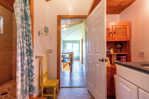 A narrow hallway with a wooden floor, a yellow chair, and a wooden door leading to a room with a window. - Wonderful hilltop house with breathtaking views (Dorset)