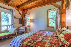 A cozy cabin room with a bed, a chair, and a window with curtains.