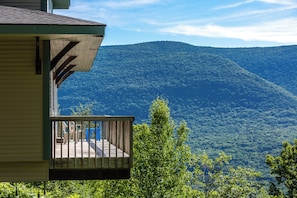 A wooden deck with a view of a forested mountain.