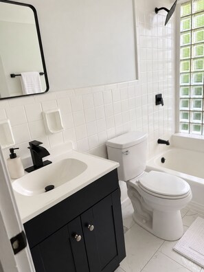A bathroom with a white sink, black cabinet, white toilet, and a bathtub. - Updated 2BR Cincinnati Apartment for Extended Stays - Unit 1 (Cincinnati)