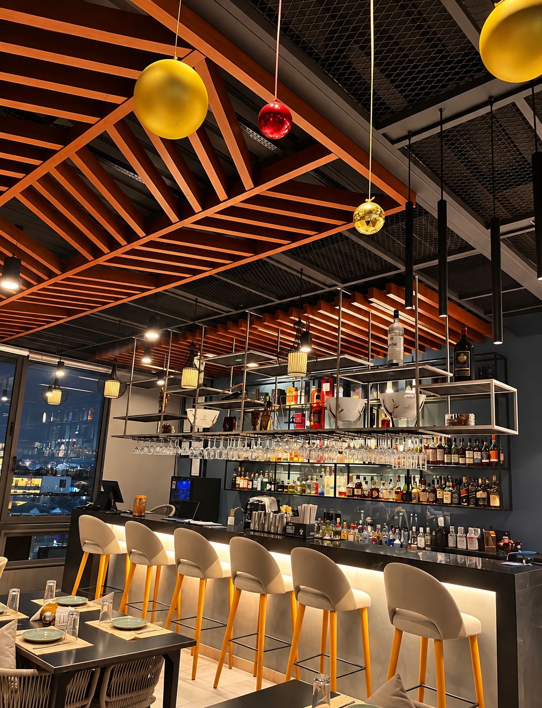 Eine Bar mit Blick auf die Stadt, moderner Beleuchtung und einer Auswahl an Flaschen.