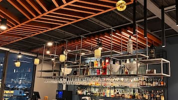 Eine Bar mit Blick auf die Stadt, moderner Beleuchtung und einer Auswahl an Flaschen.