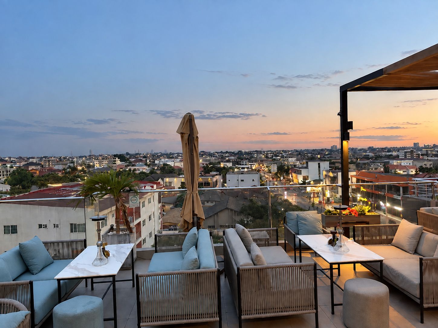 Eine Dachterrasse mit Außenbestuhlung, Blick auf die Stadtlandschaft und einem Sonnenuntergang.
