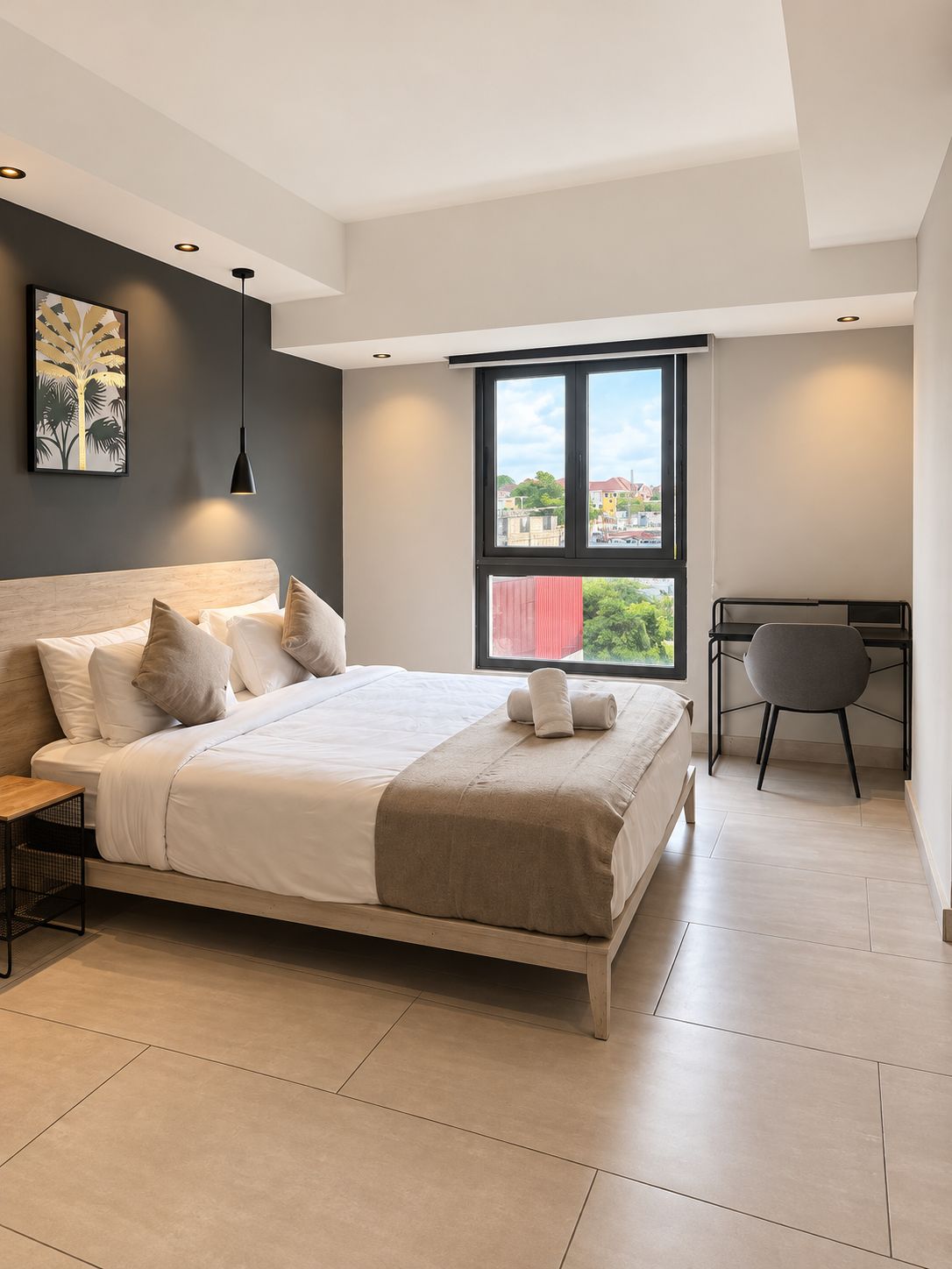 Ein modernes Schlafzimmer mit einem großen Bett, einem Schreibtisch und Blick auf die Stadt durch ein Fenster.