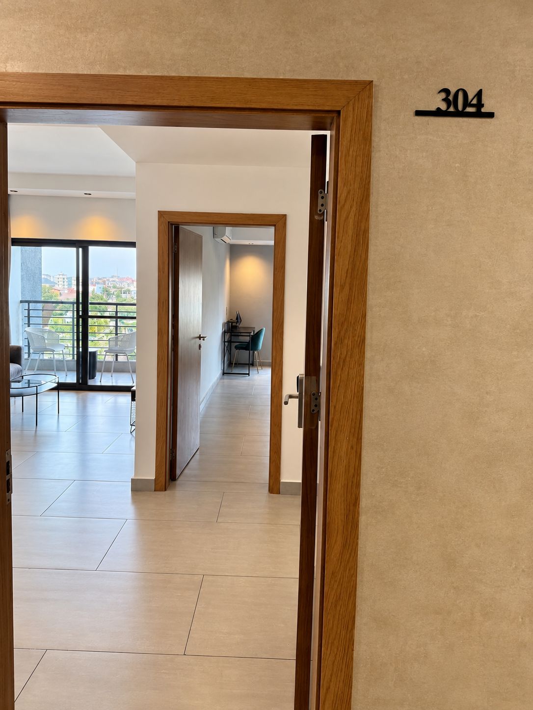 A hallway with a wooden door frame, a number sign, and a view into a room with a table and chairs.