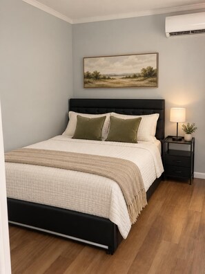 A bedroom with a bed, bedside tables, a lamp, and a painting on the wall. - Cozy Apartment with Private Entrance in Brandon! (Brandon)