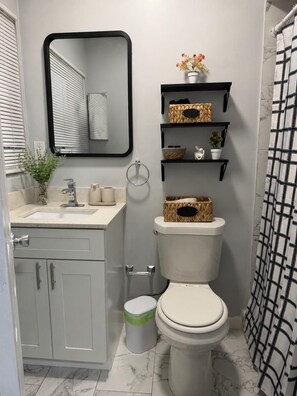 Un baño con inodoro, lavamanos, espejo y cortina de ducha.