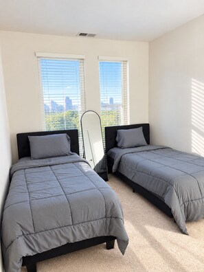 Una camera da letto con due letti, vista sulla città e finestra con tende.