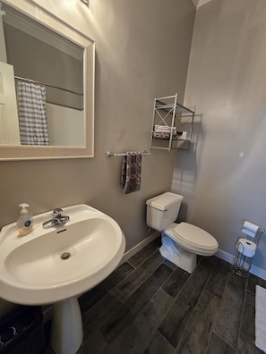 Et badeværelse med en hvid vask, toilet og et spejl.