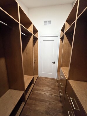 Un armario vestidor con estantes de madera y una puerta blanca.