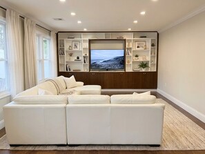 Una sala de estar moderna con un sofá modular, un televisor de pantalla plana y estanterías empotradas.