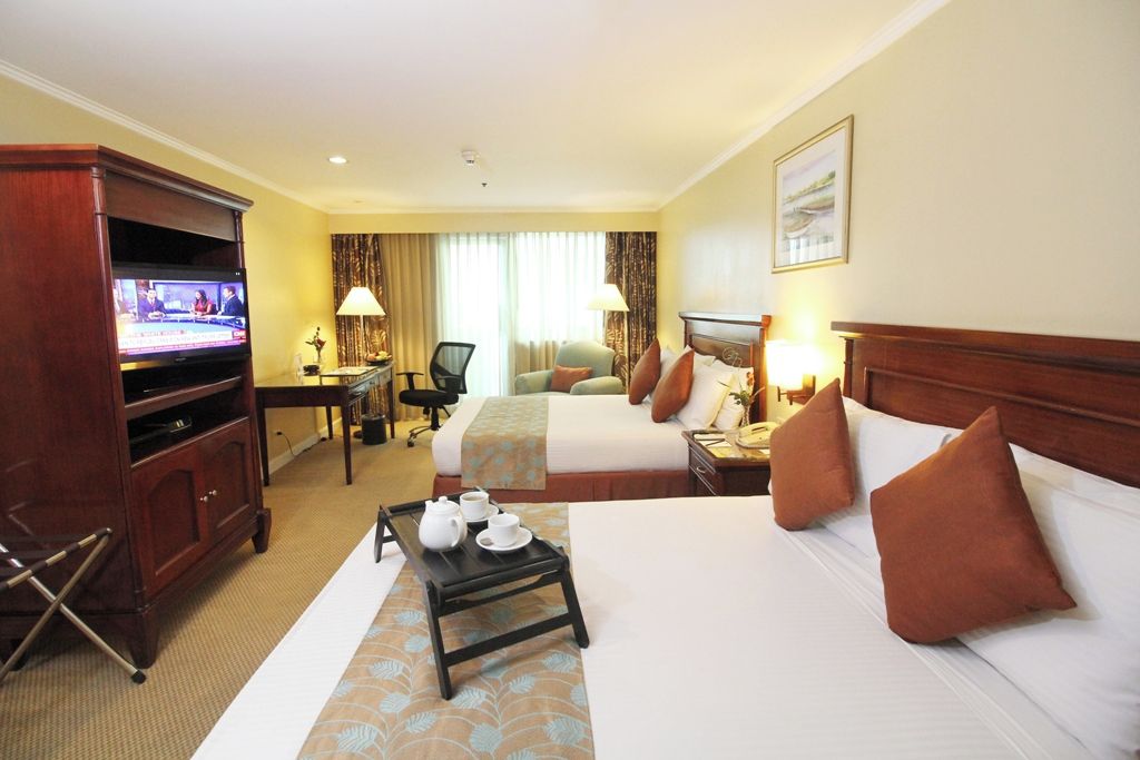 Habitación de hotel con dos camas, televisor, escritorio con silla y una mesita con bandeja de té.