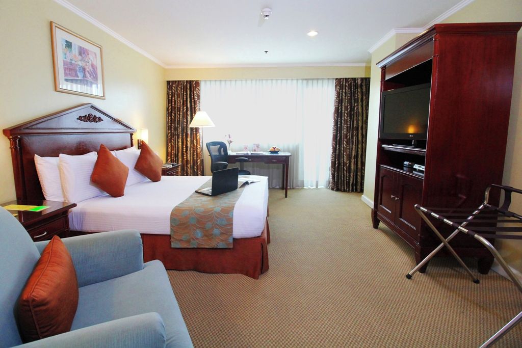 Ein Hotelzimmer mit einem Bett, einem Schreibtisch, einem Fernseher und einem Sessel.
