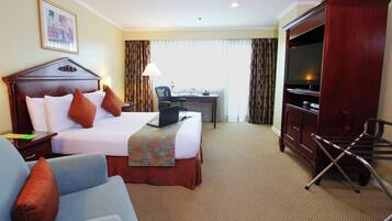 A hotel room with a bed, a desk, a television, and a chair.