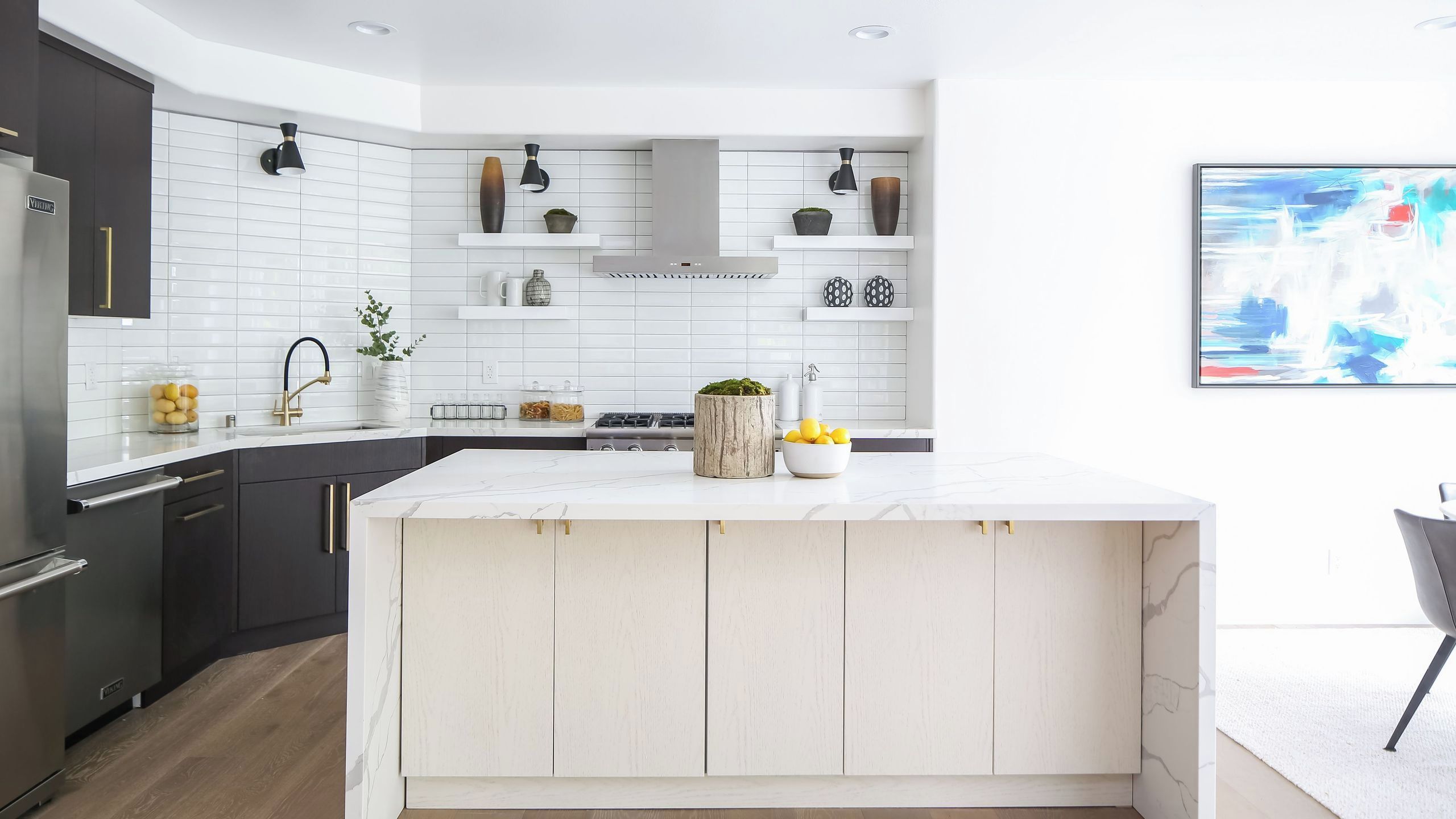 A modern kitchen with white cabinetry, a marble countertop, and a central island.