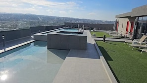 A rooftop pool area with a view of the cityscape, a small garden, and a building with red accents. - New Listing (Tijuana)