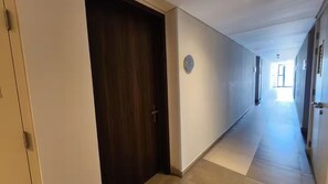 A corridor with a wooden door, a wall-mounted clock, and a tiled floor. - New Listing (Tijuana)