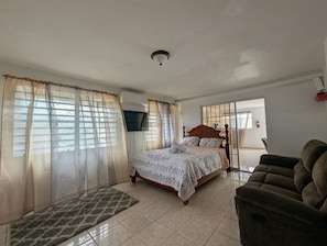A bedroom with a bed, curtains, a sofa, and a fire extinguisher. - Casa Ceiba (Ceiba)