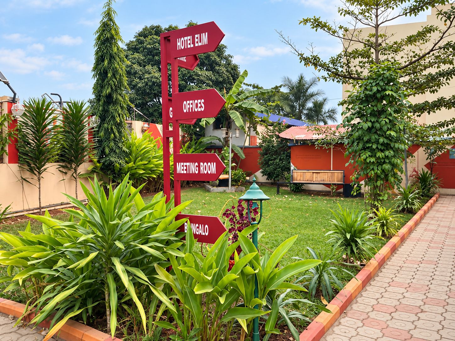 Señal direccional roja con varias flechas que indican diferentes servicios del hotel, como el hotel mismo, oficinas, una sala de reuniones y bungalows.