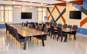 Un salón de conferencias con una larga mesa, sillas, un televisor de pantalla plana y un equipo de aire acondicionado.