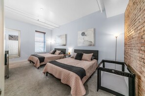 Ein Schlafzimmer mit zwei Betten, einer Ziegelwand und einer Deckenleuchte.