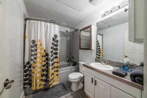Ein Badezimmer mit Duschvorhang, Toilette, Waschbecken und Spiegel.