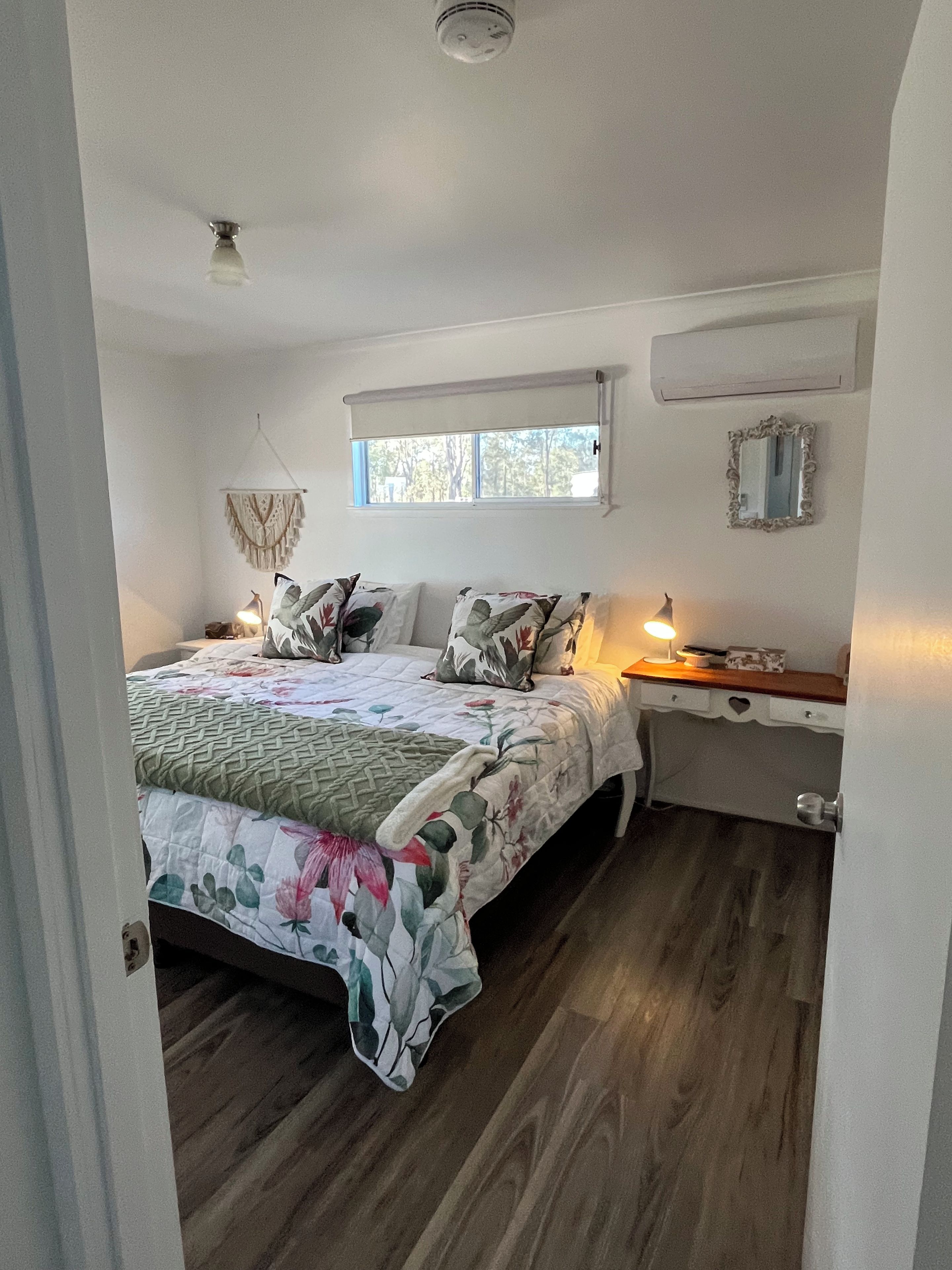 Een slaapkamer met een bed, nachtkastjes, een raam en een spiegel.
