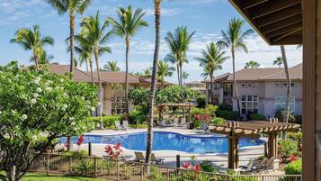 A resort with a swimming pool, palm trees, and a covered patio area.