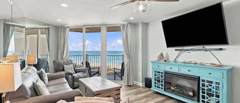 A living room with a sofa, a coffee table, a fireplace, and a television.