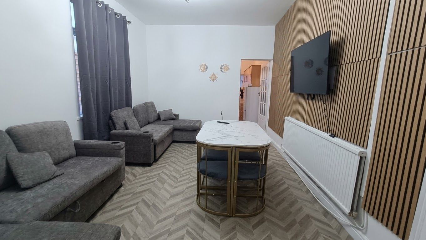Un salon avec un canapé, une table basse et un téléviseur fixé au mur.