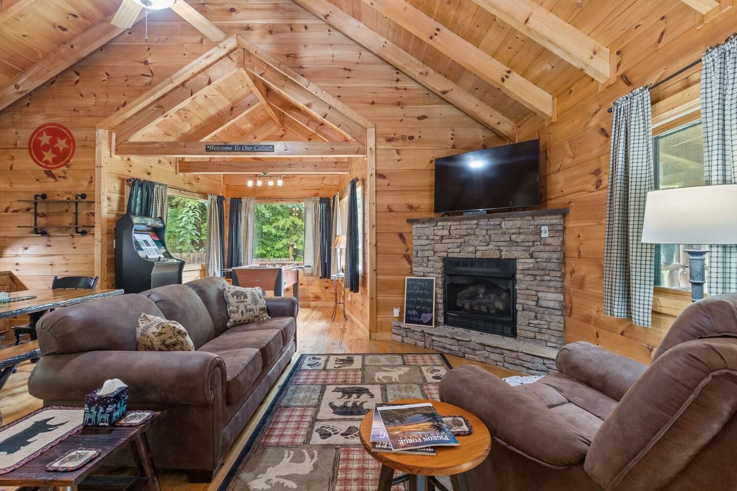 A cabin interior with a sofa set, a fireplace, a television, and a pool table.