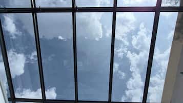 A room with a large window offering a view of the sky and clouds.