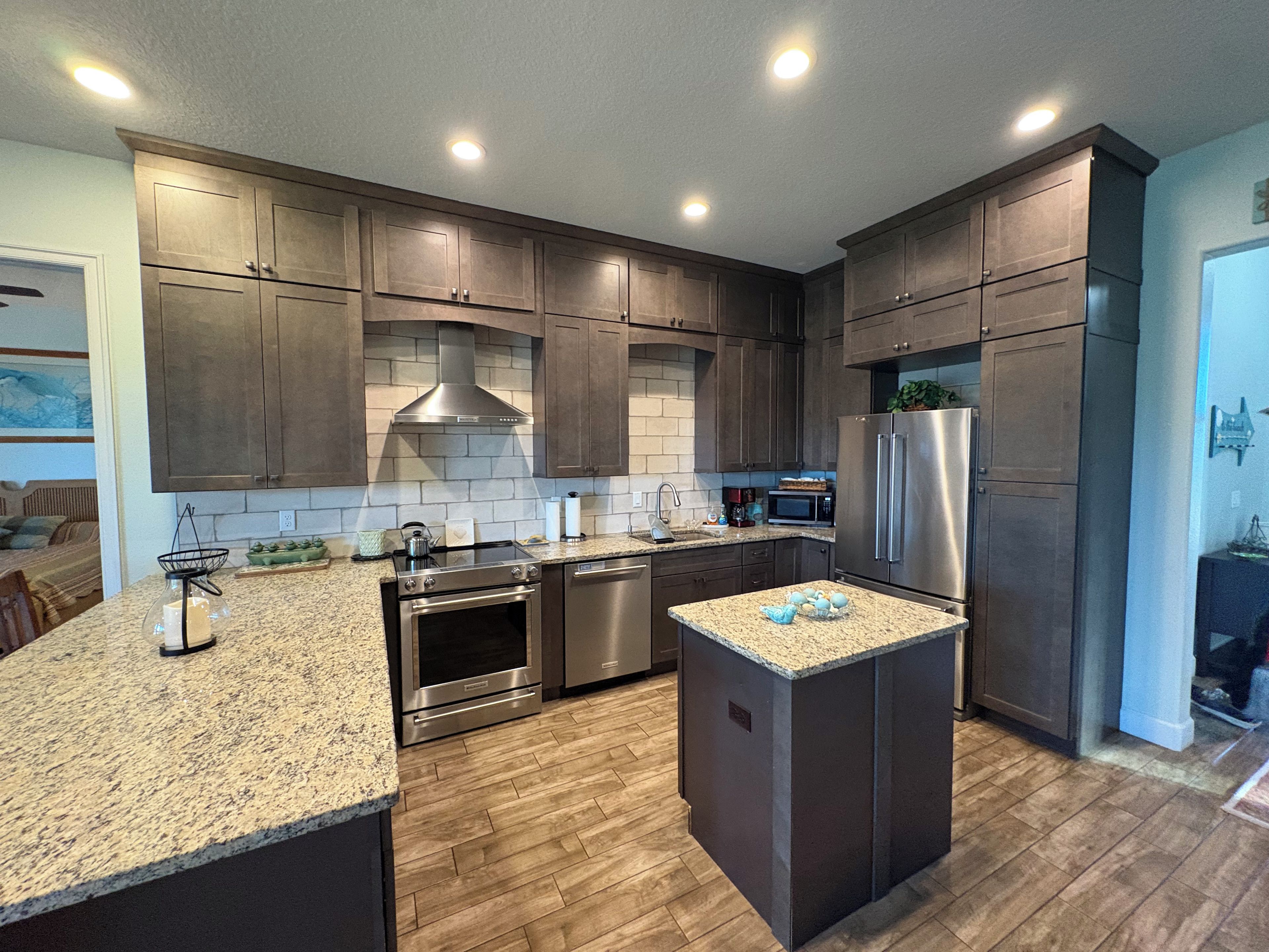 A modern kitchen with dark wood cabinets, stainless steel appliances, and a granite countertop.