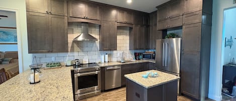A modern kitchen with dark wood cabinets, stainless steel appliances, and a granite countertop.