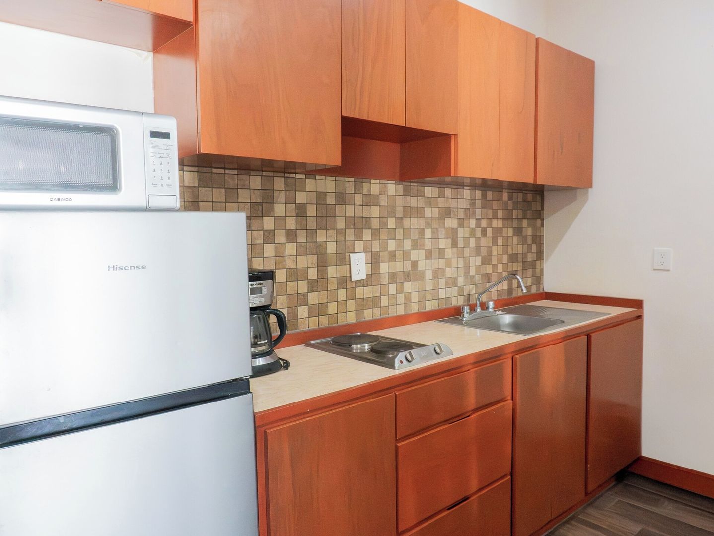 A compact kitchen with a white refrigerator, a coffee maker, and a microwave.