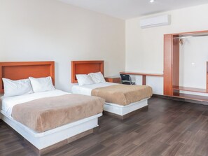 Une chambre d’hôtel avec deux lits, un bureau et un miroir.