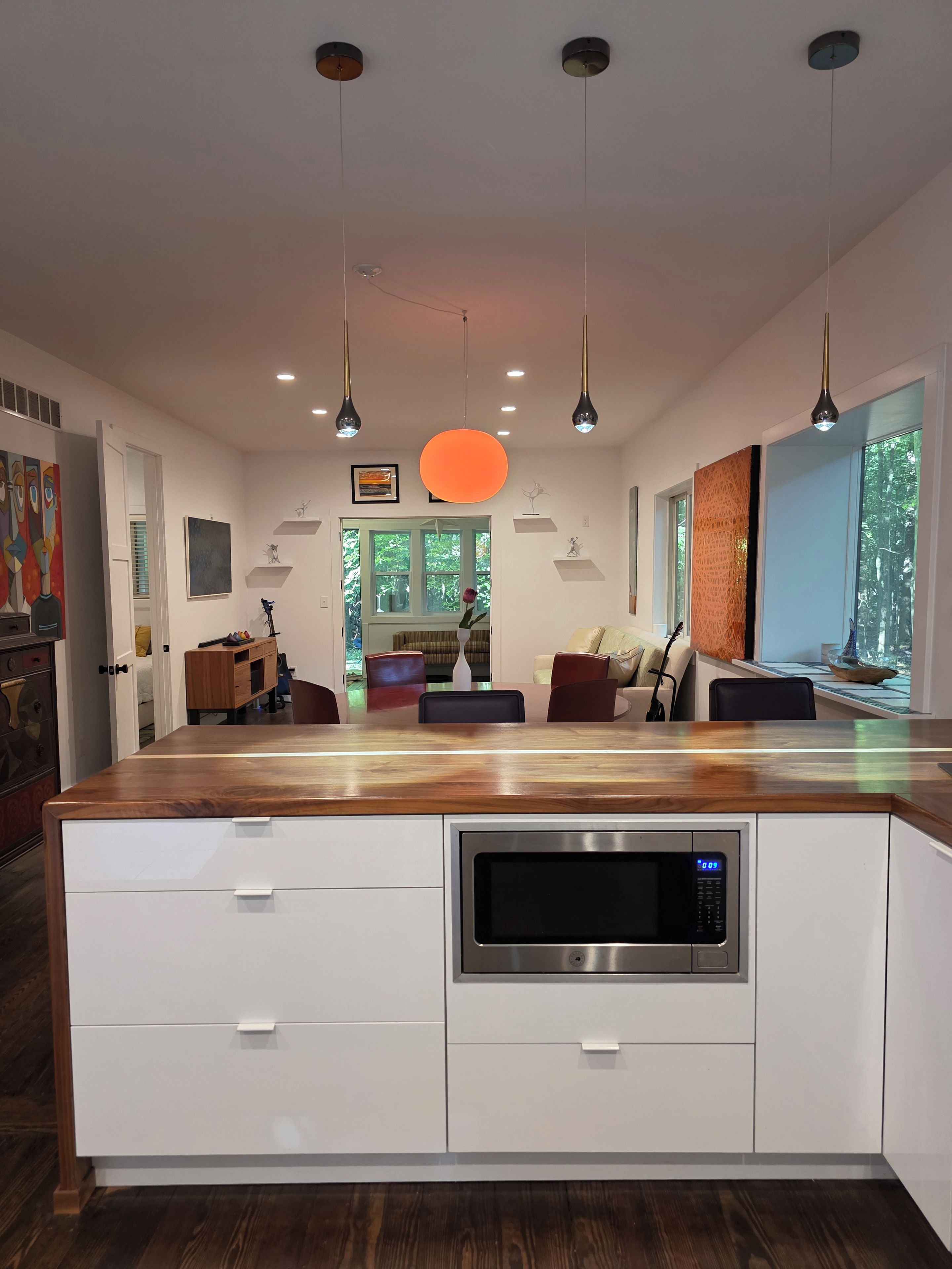 A modern kitchen with a wooden countertop, built-in microwave, and pendant lights.