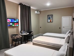 A hotel room with two beds, a desk, a chair, a TV, and an air conditioning unit. - LUNA PLAZA HOTEL TASHKENT (Tashkent)