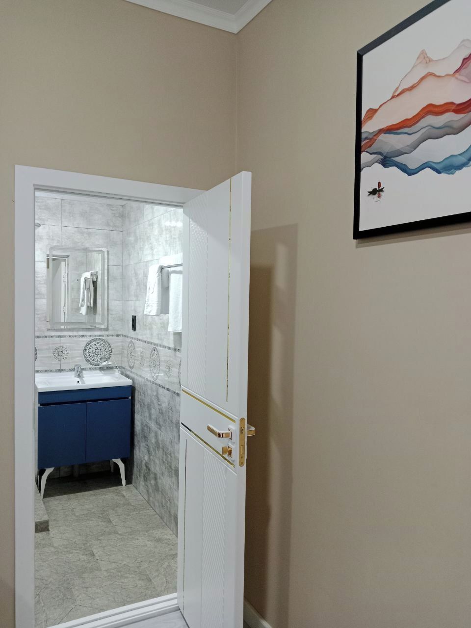 A bathroom with a white door, a blue cabinet, and a mirror.