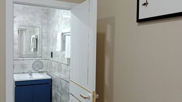 A bathroom with a white door, a blue cabinet, and a mirror.