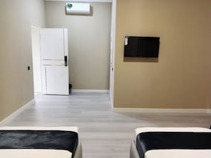 A hotel room with a bed, a television mounted on the wall, and a door leading to another room. - LUNA PLAZA HOTEL TASHKENT (Tashkent)