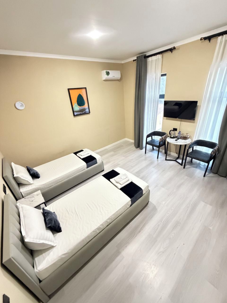 A hotel room with two beds, a TV, a small table, and a chair.