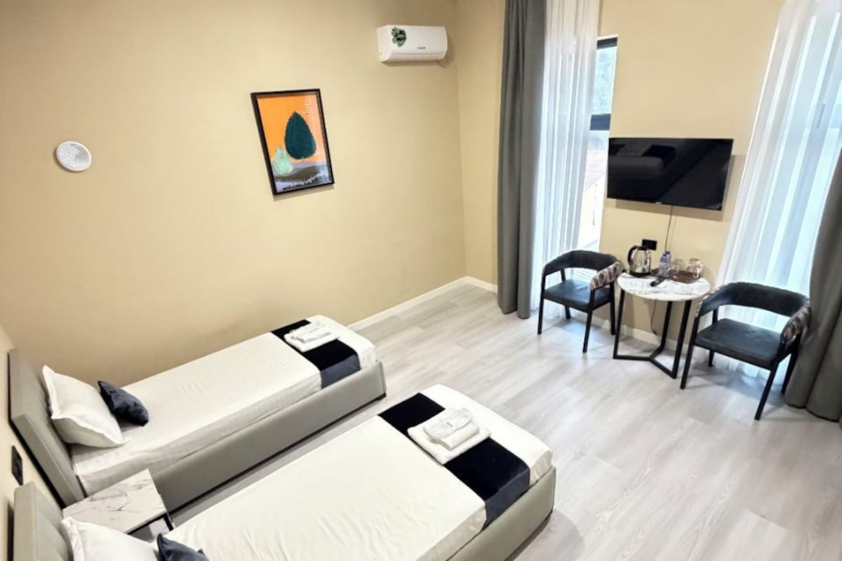 Habitació d'hotel amb dos llits, una televisió, una taula petita i una cadira.
