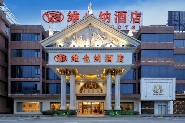 A hotel with a prominent sign, classical columns, and a modern facade. - Vienna Hotel (Weihai)
