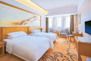 A hotel room with two beds, a desk, a chair, a TV, and a large window with curtains. - Vienna Hotel (Weihai)