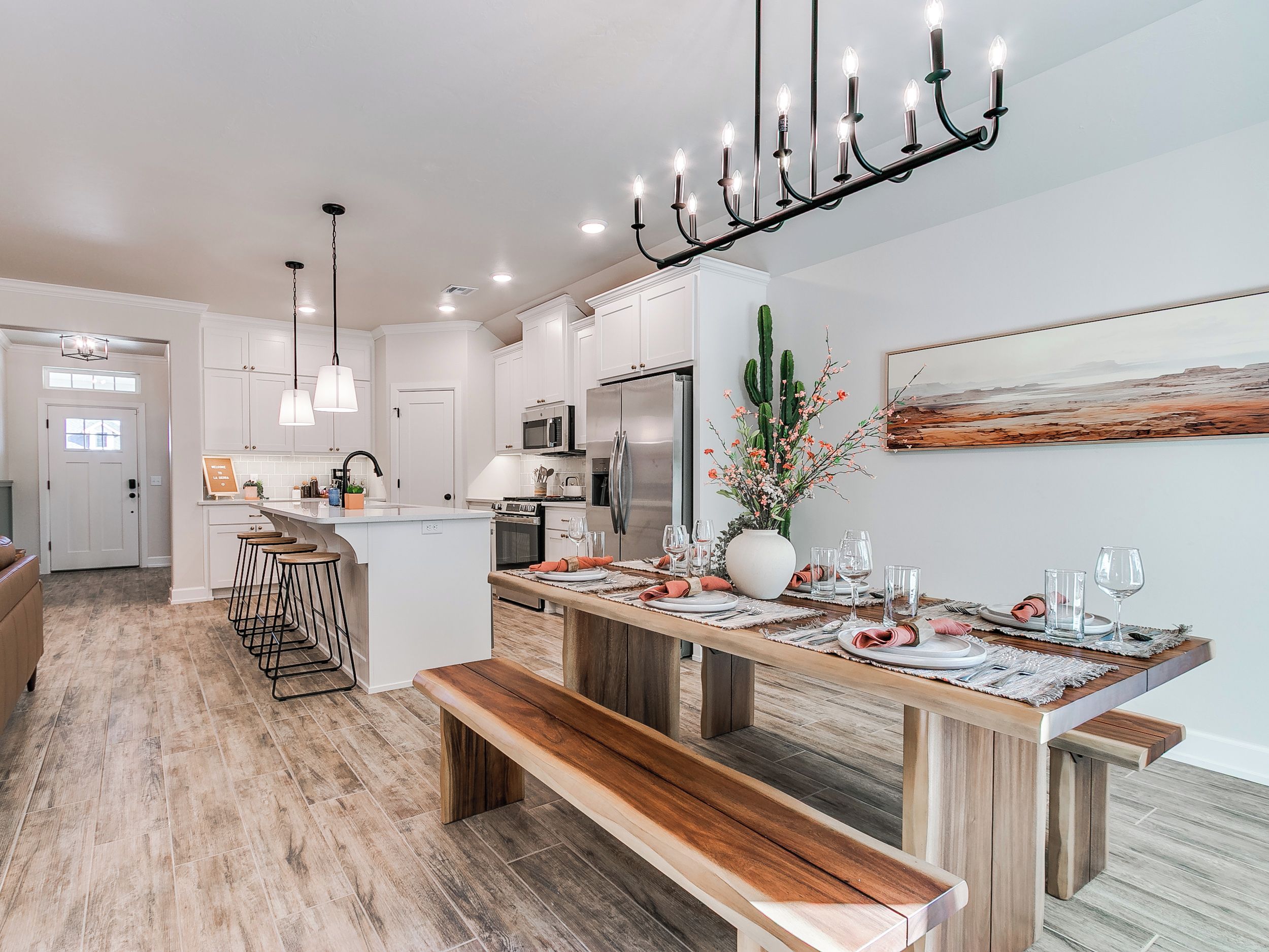 A modern kitchen with white cabinetry, a central island, and a dining area with a wooden bench and table set for six.