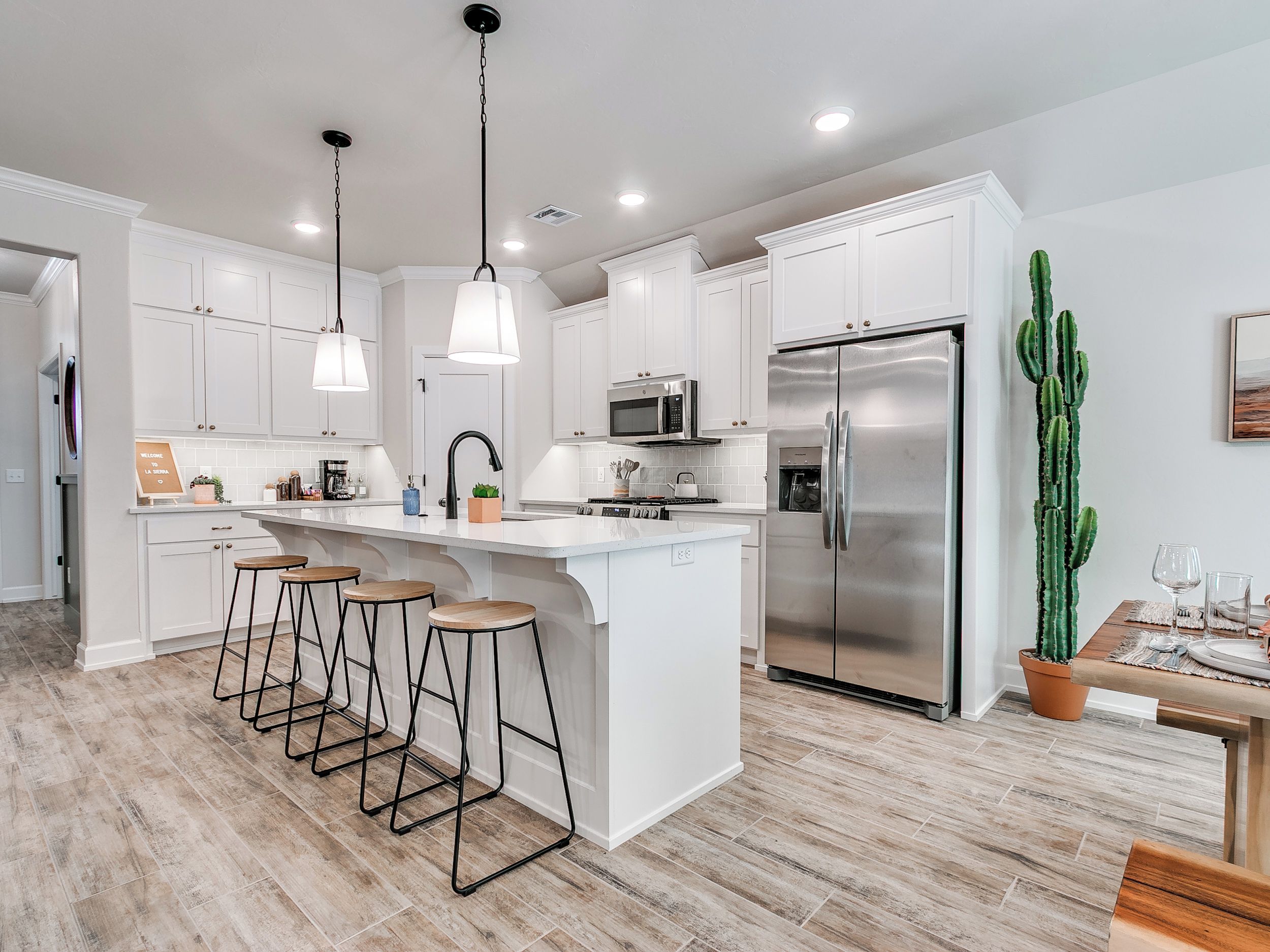 A modern kitchen with white cabinetry, stainless steel appliances, and a central island with bar stools.