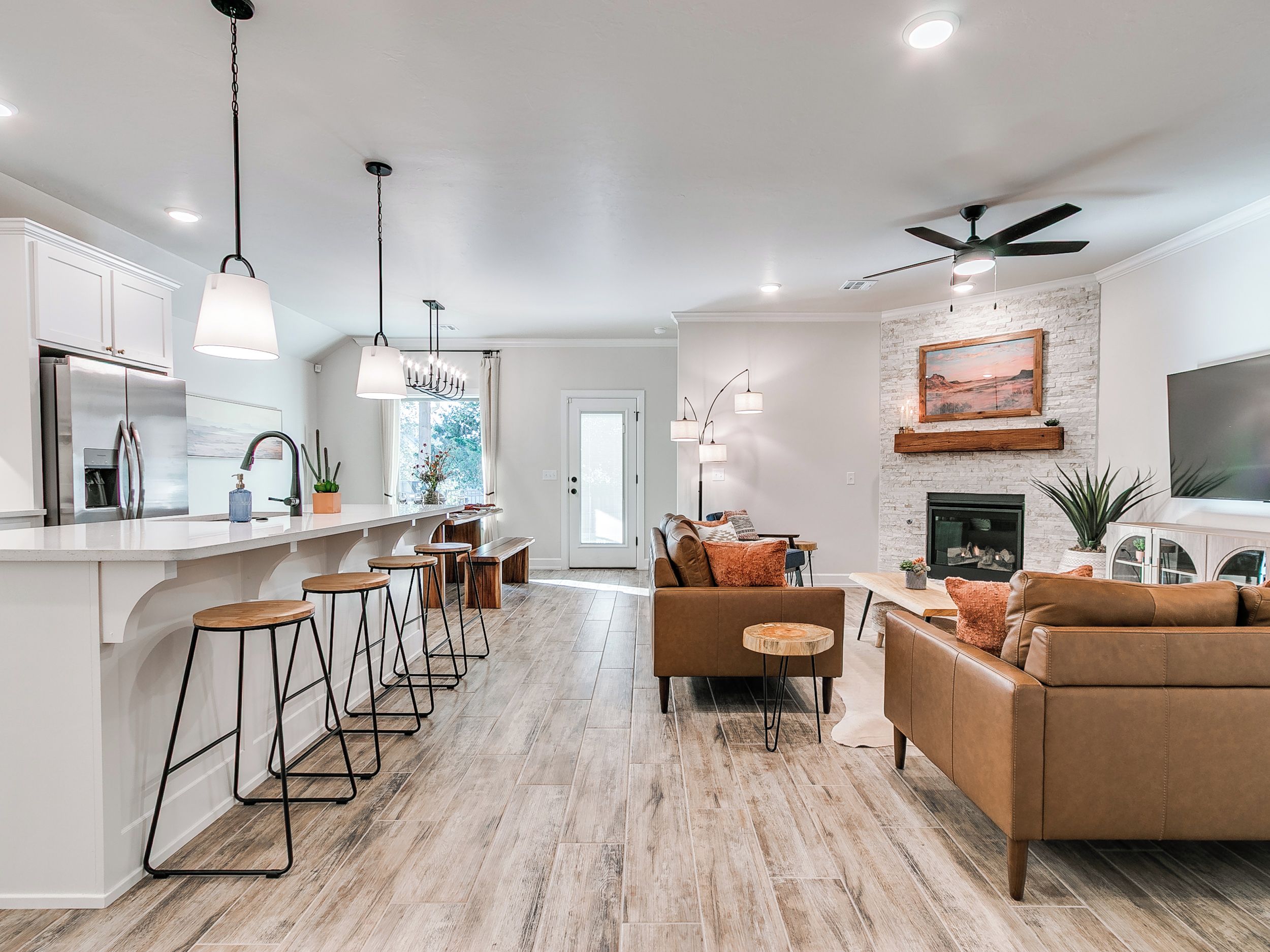 A modern kitchen with a central island, bar stools, and pendant lighting.