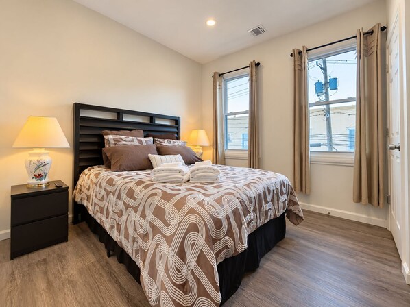 A hotel room with a bed, nightstands, a lamp, and a window with curtains.